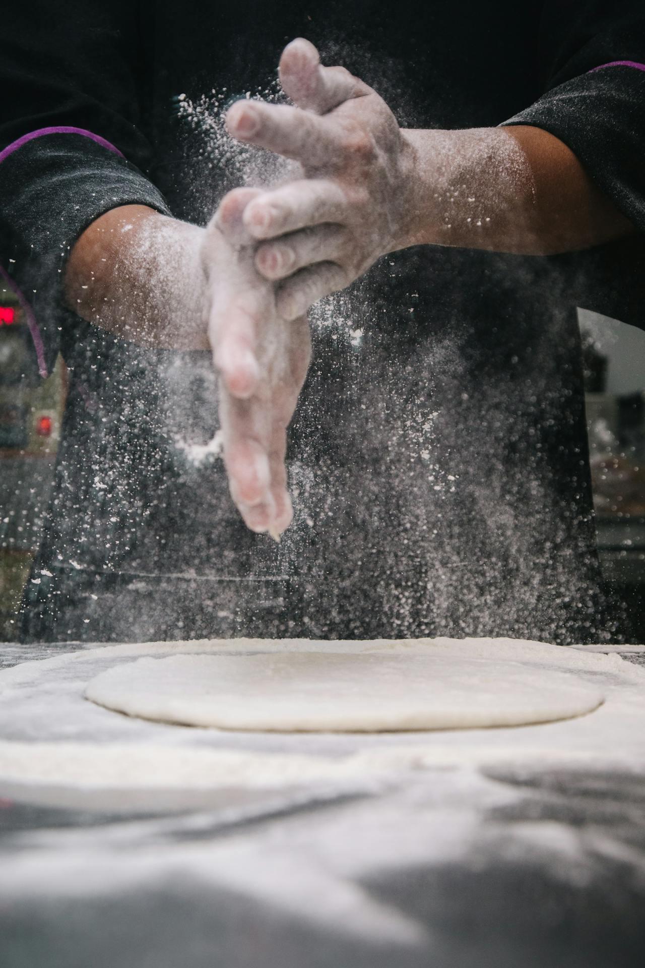 Imatge de les mans d'un cuiner preparant la massa d'una pizza. La imatge s'utilitza a la pàgina de contacte.